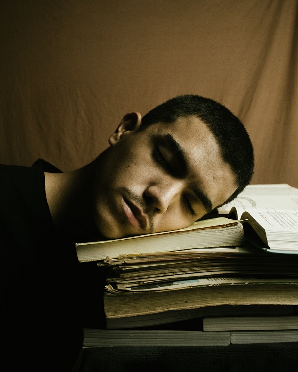 Slacker sleeping on stack of books